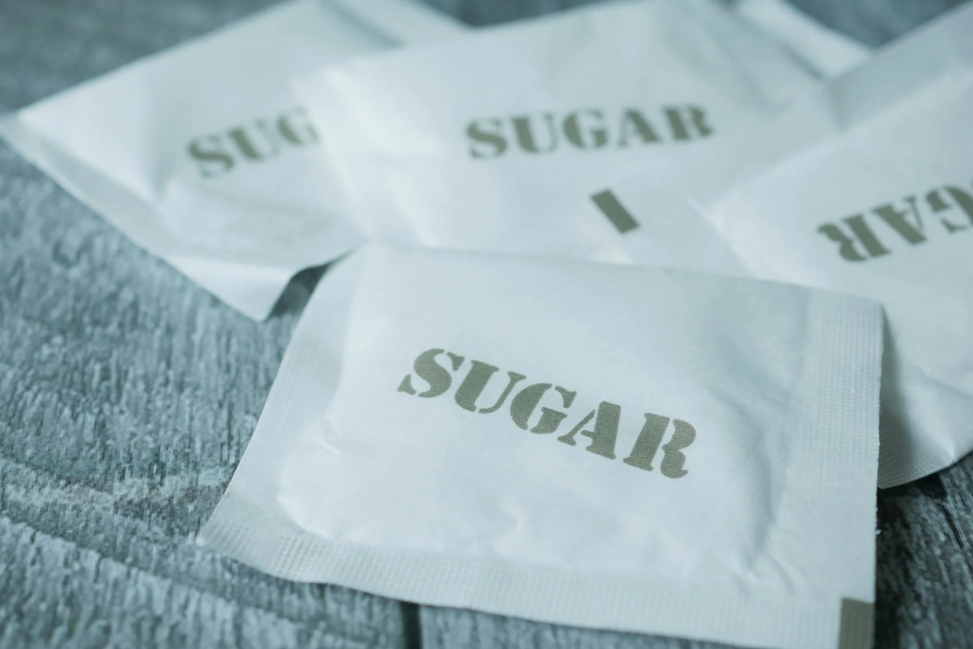 Sobres de monodosis de azúcar de papel sobre mesa de cafetería